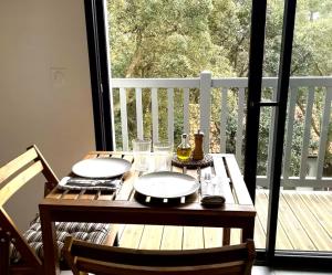 a wooden table with plates and glasses on a balcony at Appartement - Hossegor Lac in Hossegor