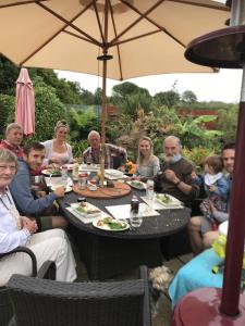 a group of people sitting around a table with an umbrella at Gwynarth B&B in Wadebridge