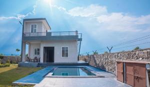 a villa with a swimming pool in front of a house at Silverleaf Homestay in Borāj +3 photos