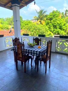 a table and chairs on a porch with a view of trees at Sylt Haus in Beruwala