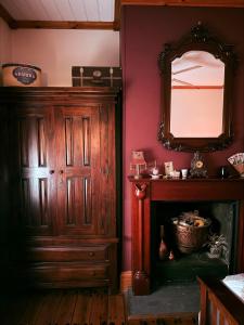 a living room with a mirror and a fireplace at Barossa Valley’s Captain Rodda’s Cottage in Angaston
