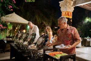 een man die een bord met eten vasthoudt op een buffet bij Mahagiri Villas Sanur in Sanur +77 foto's