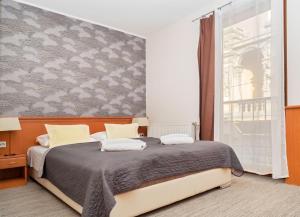 een slaapkamer met een bed en een groot raam bij König Hotel in Pécs