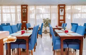 een eetkamer met blauwe stoelen en houten tafels bij König Hotel in Pécs