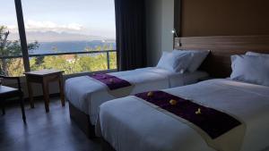 a hotel room with two beds and a large window at Bella Vista Premium Homestay in Banyuwangi