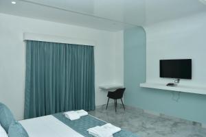a bedroom with a bed with a television and a chair at Silver Stone Park Resort, Kovilpatti in Kovilpatti