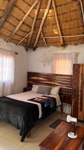 a bedroom with a bed and a table and windows at Edsam Lodge in Divundu
