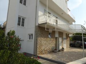 a white building with a balcony and a parking lot at Apartments Bojanic in Vodice