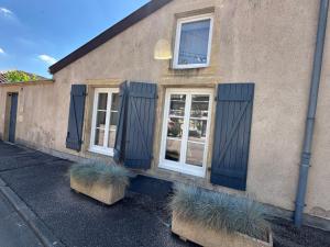 a building with blue shuttered windows and two plants at la grange aux oiseaux in Arnaville