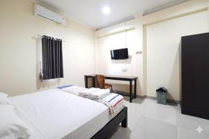 a bedroom with a bed and a desk and a tv at OYO 95059 Ikon Guesthouse in Sengata