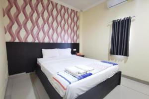 a bedroom with a bed with two towels on it at OYO 95059 Ikon Guesthouse in Sengata