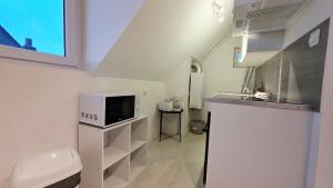 a white bathroom with a sink and a microwave at Studio Foch 4 in Grand-Fort-Philippe
