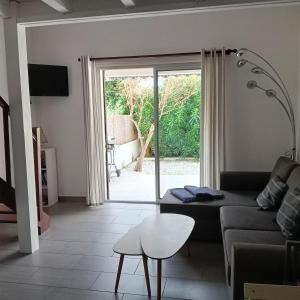 a living room with a couch and a sliding glass door at La casa du creux in Valras-Plage