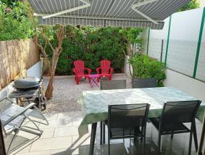 a patio with a table and chairs and a grill at La casa du creux in Valras-Plage
