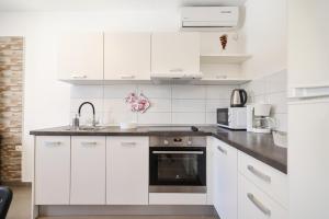 a white kitchen with a sink and a stove at Villa Feliks in Ljubač
