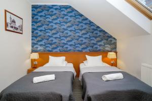 twee bedden in een kamer met een blauwe muur bij König Hotel in Pécs