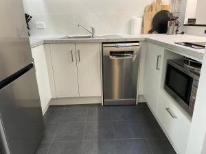 a kitchen with white cabinets and a stainless steel dishwasher at Downtown, Contemporary and Artistic in Albany