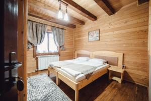 een slaapkamer met een bed in een houten kamer bij Pensiune Borsa in Borşa