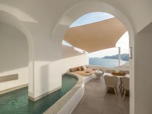 a living room with a swimming pool and a table at Aspaki by Art Maisons in Oia