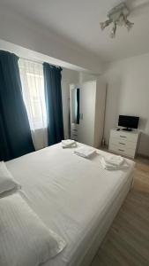 a bedroom with a large white bed with blue curtains at La Playa Residence in Năvodari