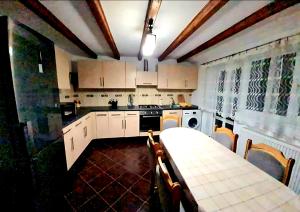 a kitchen with white cabinets and a table with chairs at Casa Ostrov in Călimăneşti