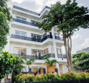 a white building with a tree in front of it at Amaltaash by Sandane Homes in Greater Noida