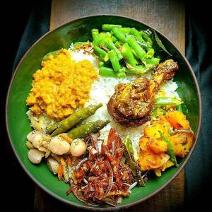 a green plate of food with rice and vegetables at River cottage Demodara in Demodera