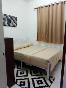 a bed in a room with a curtain and a rug at Tipika Guest House - di Pasir Pekan sempadan 3 Daerah KB, Pasir Mas & Tumpat in Tumpat