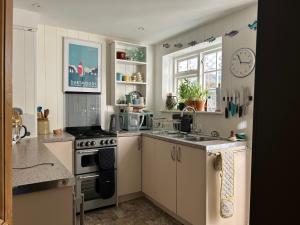 a kitchen with white cabinets and a stove top oven at Laurel Cottage in Exmouth