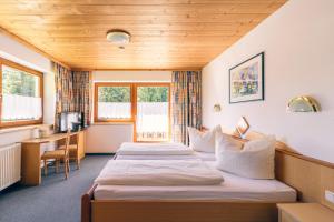 a hotel room with two beds and a desk at Pension Sattelkopf in Sankt Anton am Arlberg