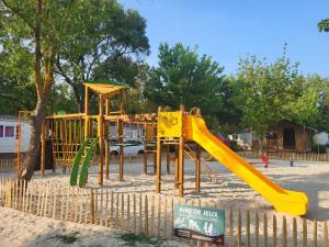 a playground with a yellow slide in the sand at Camping Le Val de Cesse in Mirepeisset