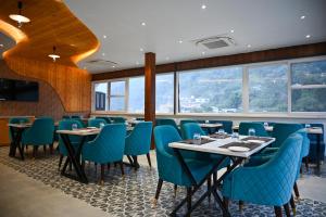 a dining room with tables and blue chairs at Amritara Chakra River Resort - Closest Luxury Resort to Neelkanth Temple in Mohan Chatti