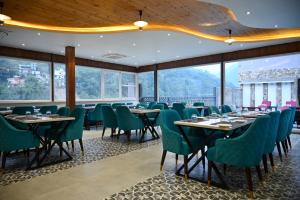 a dining room with tables and chairs and large windows at Amritara Chakra River Resort - Closest Luxury Resort to Neelkanth Temple in Mohan Chatti