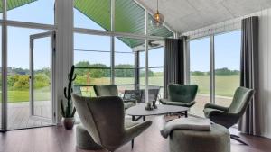 a living room with chairs and a table and large windows at Villavilla 546 - Hostrup Strand, Limfjorden in Spottrup