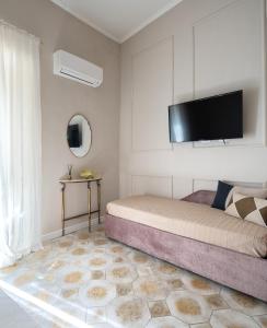 a bedroom with a bed with a flat screen tv on the wall at Ziolì Apartment in Noto