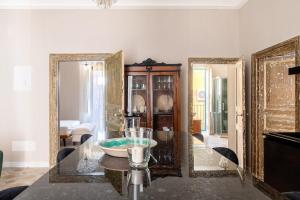 a dining room with a glass table and mirrors at Ziolì Apartment in Noto