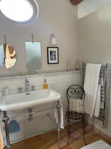 a bathroom with a sink and a mirror and a chair at Le Mas de la Rose in Taradeau +37 photos