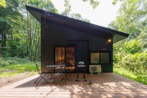 a black tiny house with a wooden deck at Narusawa MADOKA in Narusawa