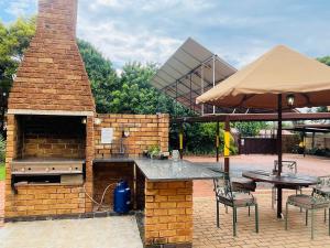 a patio with a brick oven and a table with chairs at Clubview Guest House in Centurion