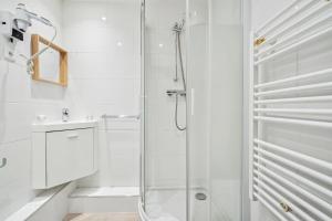 a white bathroom with a shower and a sink at Hôtel Mazagran in Paris +7 photos