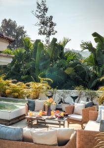 a patio with chairs and tables and a pool at LohonoStays Castello Villa 2 in Assagao