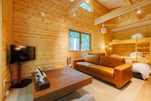 a living room with a couch and a tv in a log cabin at Narusawa MADOKA in Narusawa
