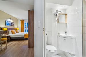 a bathroom with a toilet and a bedroom with a bed at Hôtel Mazagran in Paris