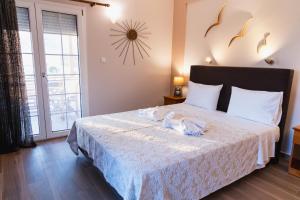 a bedroom with a bed with white sheets and a window at Alkiones in Platy