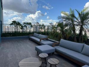 a patio with couches and tables on a balcony at Luxo e Aconchego 1Qt Com Sacada GY03 proximo Vaca Brava in Goiânia