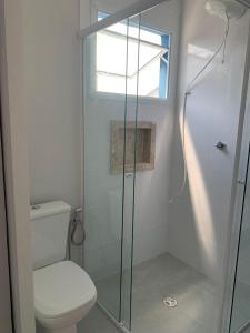 a bathroom with a toilet and a glass shower at Lua nova Studio I in Caraguatatuba +10 photos