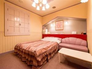 a bedroom with a large bed and a couch at ホテルツクバランド in Tōgane