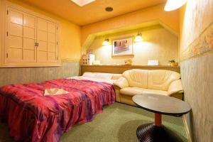 a bedroom with a bed and a chair and a table at ホテルツクバランド in Tōgane