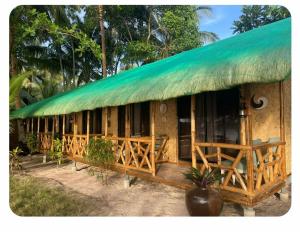 a house with a green roof with a porch at Ocam Ocam Bayside Lodge in Busuanga