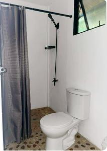 a bathroom with a toilet with a shower curtain at Ocam Ocam Bayside Lodge in Busuanga